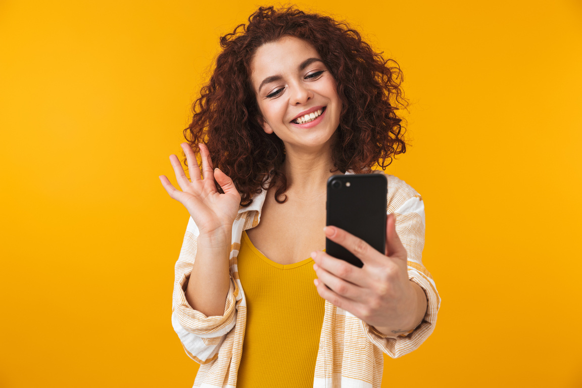 Curly-haired Woman Waving Hello to Someone on Video Call